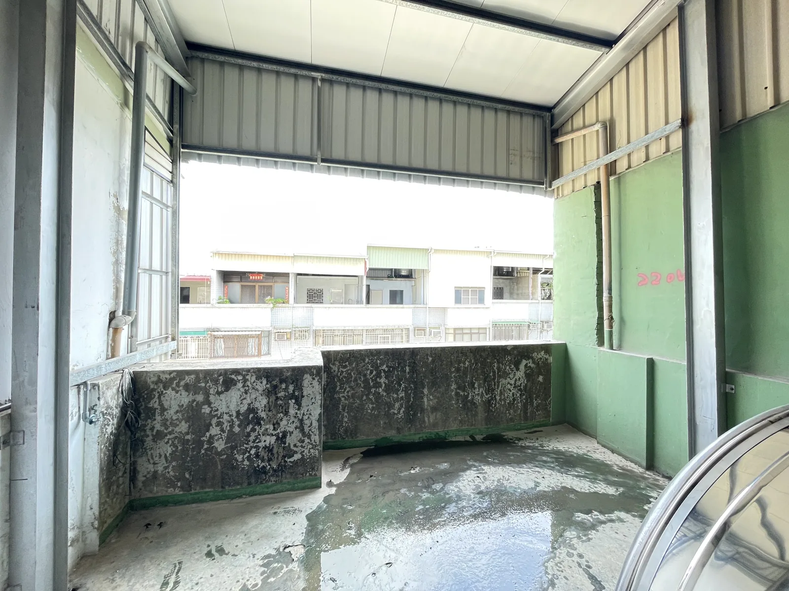 施工中：拆除舊隔間後的頂樓陽台，鐵皮屋頂與老舊女兒牆仍在